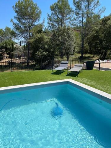 une piscine bleue dans une cour avec deux bancs dans l'établissement Villa Coco - Superbe villa avec piscine privée grand jardin et terrain de boules, aux Arcs-sur-Argens