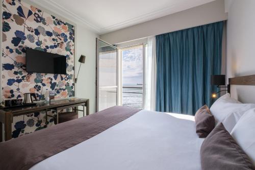a hotel room with a bed and a window at Hotel & Spa Les Roches Noires in Les Sables-dʼOlonne