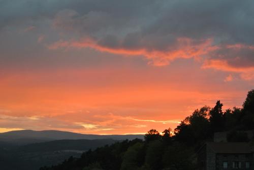 a sunset in the mountains with trees in the foreground at Art et Création in Saint-Bérain