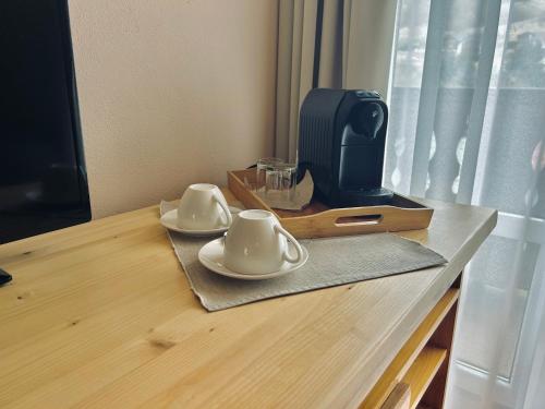 two cups and saucers on a table with a microwave at Penzión Liezky in Mýto pod Ďumbierom