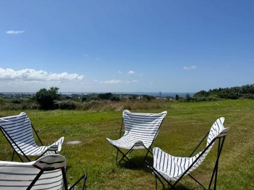 a group of chairs sitting in a field at Villa Kermilon sea view and quiet 12p in Plougasnou