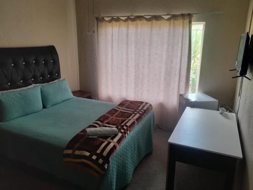 Un dormitorio con una cama y un sofá y una ventana. en Wallace place guest house, en Polokwane