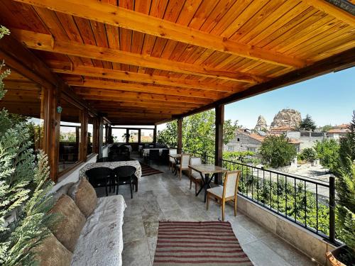 an outdoor patio with a wooden ceiling and tables and chairs at Anatolia Raymonde Cave House in Uçhisar