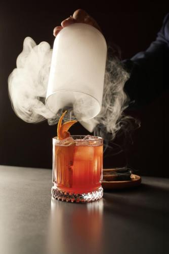 a person is lighting a drink with a candle at Hotel & Spa REGENT PETITE FRANCE By Stay Collection in Strasbourg