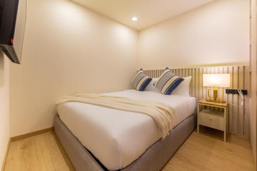 a bedroom with a large white bed with blue pillows at The Ozone Residences Bangtao in Phuket