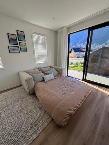 a large bed in a bedroom with a large window at One bedroom apartment in Queenstown Airport