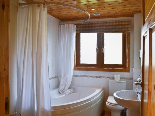a bathroom with a tub and a toilet and a sink at The Shank in Fritton Norfolk