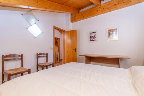 a bedroom with a white bed and two chairs at Casa dei Gigli in Selva di Cadore