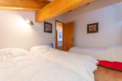 two beds in a room with white sheets at Casa dei Gigli in Selva di Cadore