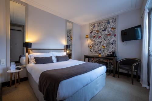 a hotel room with a large bed and a tv at Hotel & Spa Les Roches Noires in Les Sables-dʼOlonne