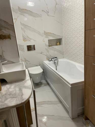 a bathroom with a sink and a tub and a toilet at Magiczny apartament in Duszniki Zdrój