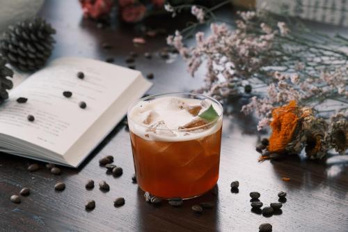 a drink sitting on a table next to a book at Lijiang Jijian Xiangwang SOOOAN Luxury Resort Hotel in Lijiang