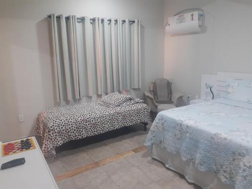 a bedroom with two beds and a chair in it at Casa Da Vovó Helena in Vila Velha