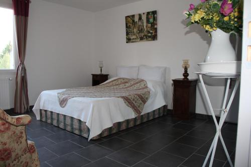 1 dormitorio con 1 cama y un jarrón de flores en Villa des Oliviers, en Fontvieille