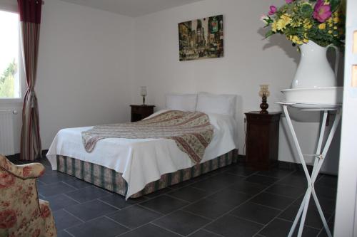 een slaapkamer met een bed en een vaas met bloemen bij Villa des Oliviers in Fontvieille