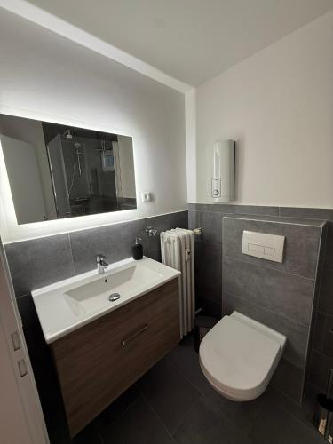 a bathroom with a sink and a toilet and a mirror at Frisch renoviertes Appartement in Mönchengladbach