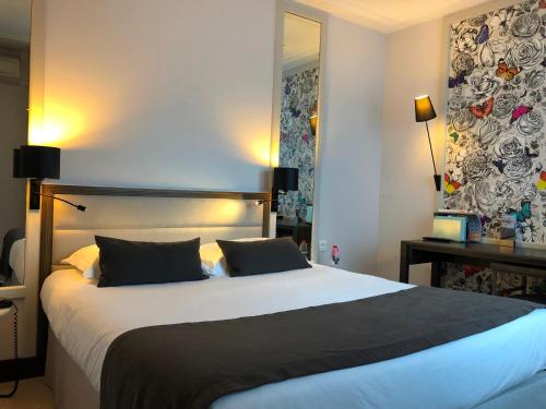 a bedroom with a large bed and a mirror at Hotel & Spa Les Roches Noires in Les Sables-dʼOlonne
