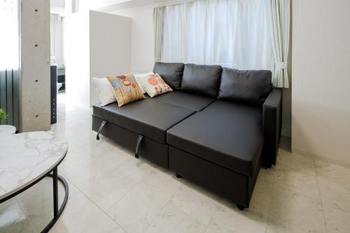 - un canapé en cuir noir dans le salon dans l'établissement LAN Sapporo Nijo Market, à Sapporo