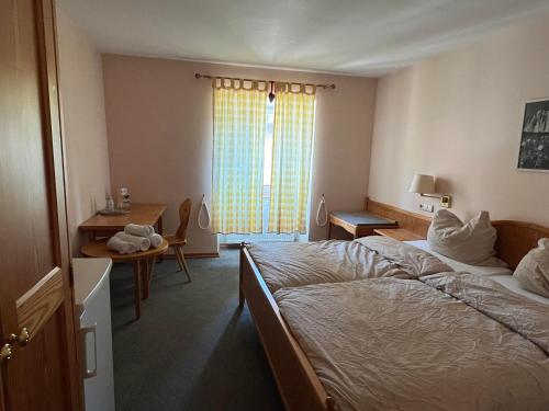 a bedroom with a bed and a desk and a window at Hotel Restaurant Lavelle in Gräfinthal