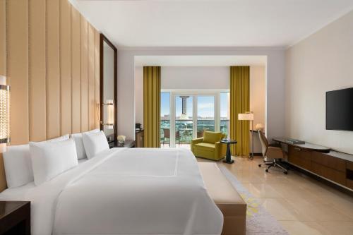 a bedroom with a large white bed and a desk at Rixos Marina Abu Dhabi in Abu Dhabi