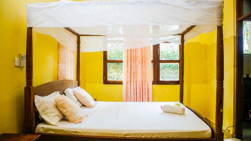 a yellow bedroom with a bed with a canopy at Diani Villa in Gatunga