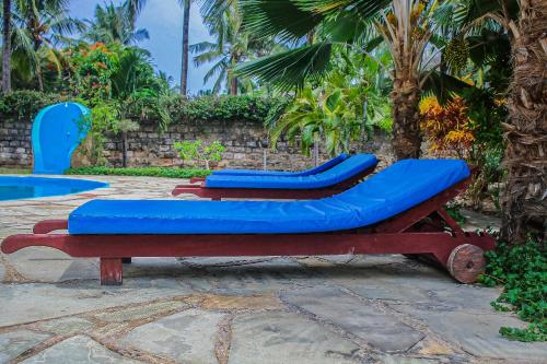 two blue chairs sitting next to a pool at Diani Villa in Gatunga