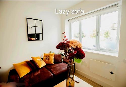 a living room with a couch and a vase with flowers at Hidden Kingston Vale-2 Bed in New Malden