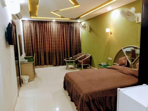 a bedroom with a bed and a chair in a room at Hotel City View Peshawar in Peshawar