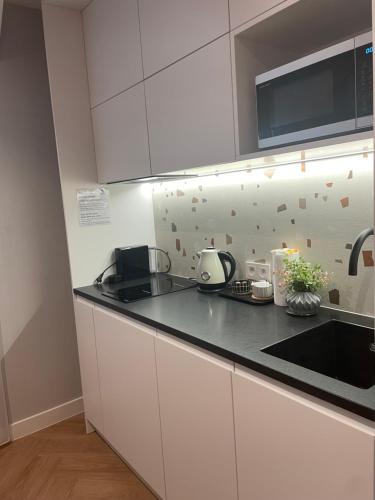 a kitchen with white cabinets and a black counter top at Luxury Apartments Gdansk in Gdańsk
