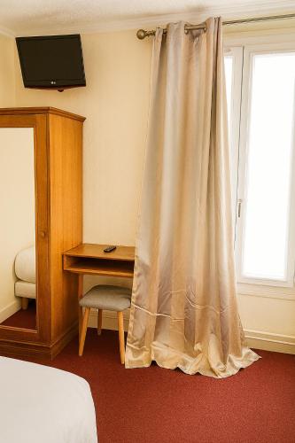 a bedroom with a bed and a desk and a curtain at Hotel Paris Bercy in Paris
