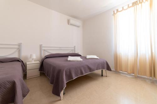 Un dormitorio blanco con dos camas y una ventana. en Villa Brigida Beach & Pool, en Ascea