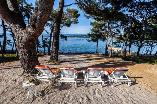 eine Gruppe Stühle und ein Tisch am Strand in der Unterkunft Apartments Mare & Mons Deluxe in Malinska