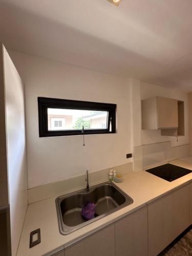 eine Küche mit Spüle und Fenster in der Unterkunft Poolside Cottage in Lubao