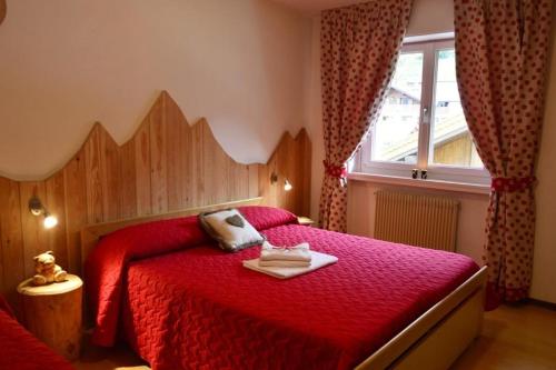a bedroom with a red bed with a red comforter at Appartamenti Viviani in Pinzolo