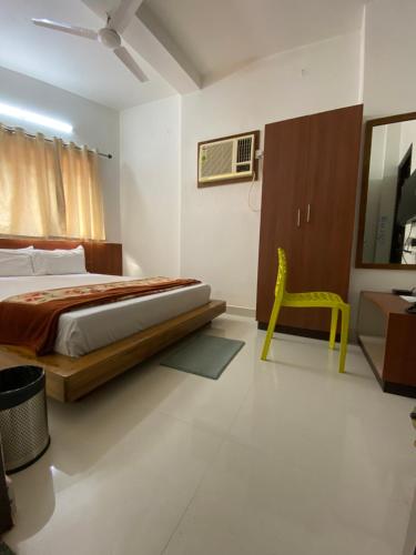 a bedroom with a bed and a yellow chair at Lake Land Guest House in Kolkata