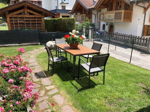 a wooden table with chairs and a pot of flowers on it at Appartamenti Viviani in Pinzolo