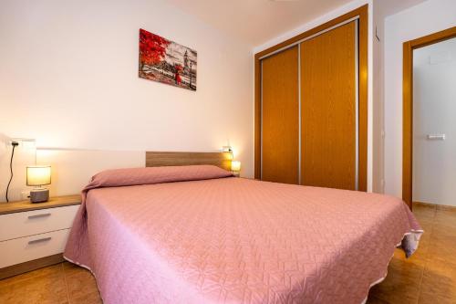 a bedroom with a bed with a pink bedspread at Acrópolis Vidaber in Oropesa del Mar