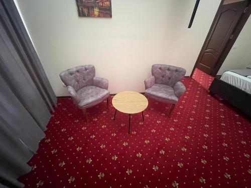 two chairs and a table in a room with a red carpet at Vila Premiere Bistro-Spa in Piatra Neamţ