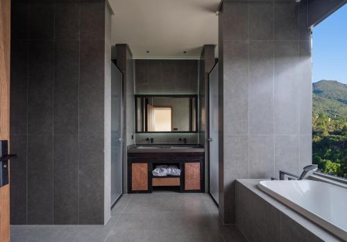 a bathroom with a tub and a sink and a mirror at Lijiang Jijian Xiangwang SOOOAN Luxury Resort Hotel in Lijiang