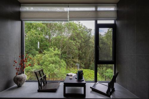a room with a table and chairs and a large window at Lijiang Jijian Xiangwang SOOOAN Luxury Resort Hotel in Lijiang