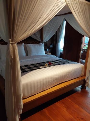 a bedroom with a canopy bed with white sheets at Nabali House in Kerobokan