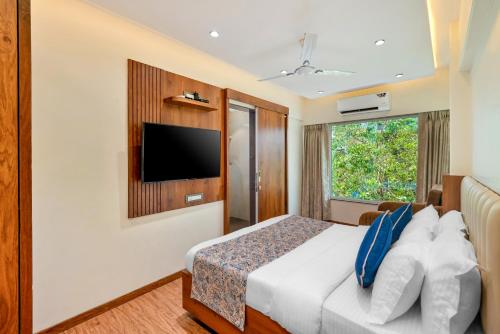 una camera d'albergo con un letto e una televisione di Hotel Kalpana Palace, Mumbai a Mumbai