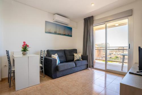 a living room with a couch and a sliding glass door at Acrópolis Vidaber in Oropesa del Mar