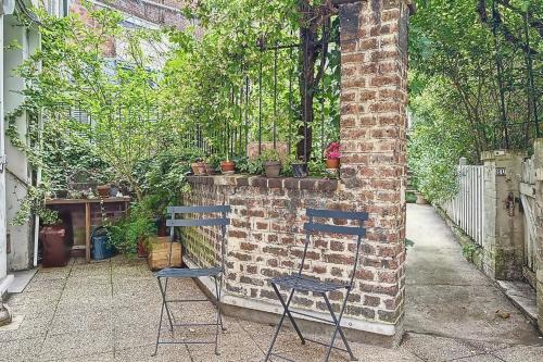 deux chaises assises à côté d'un mur de briques avec des plantes dans l'établissement Cosy studio just a stone's throw from Montmartre, à Paris