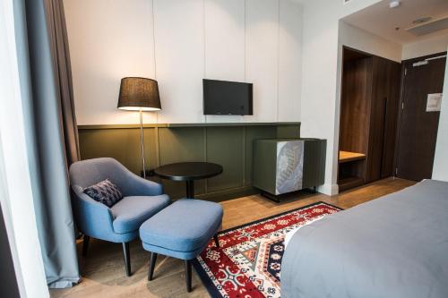 a hotel room with a bed and two chairs and a tv at Holiday Inn Telavi by IHG in Tʼelavi