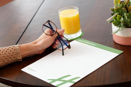 a person holding a paper with a glass of orange juice at Holiday Inn Telavi by IHG in Tʼelavi