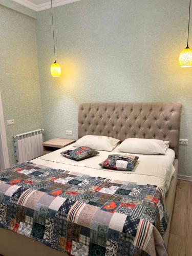 a bedroom with a bed with a quilt and two pillows at Wellconect in Kutaisi