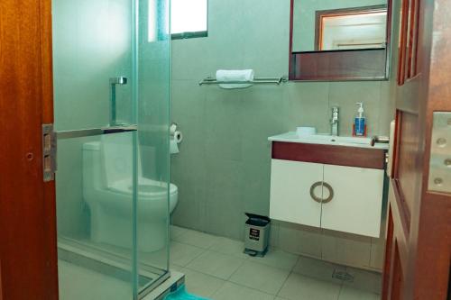 a bathroom with a toilet and a glass shower at West Sand Holidays LICENSED BY THE TOURISM AUTHORITY 09926 in Flic-en-Flac
