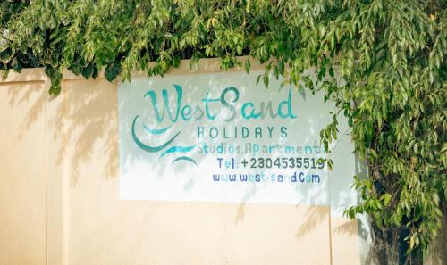 a sign on the side of a wall with trees at West Sand Holidays LICENSED BY THE TOURISM AUTHORITY 09926 in Flic-en-Flac