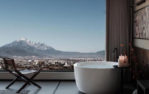 a bathroom with a tub and a chair in front of a window at Lijiang Jijian Xiangwang SOOOAN Luxury Resort Hotel in Lijiang